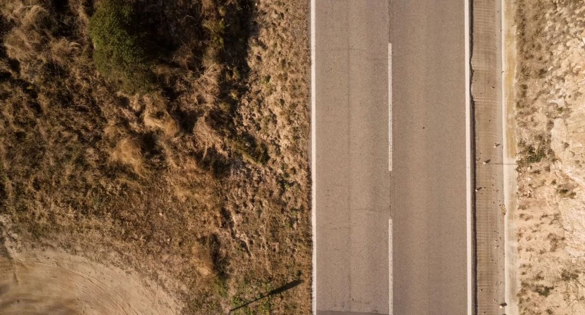 Zdjęcie ilustracyjne: dronowy widok słonecznej wiejskiej drogi z suchą roślinnością. Droga krajowa między Brodnicą a Tamą Brodzką ma być jak nowa za ponad cztery lata. Fot. Danny Hollander / Pexels