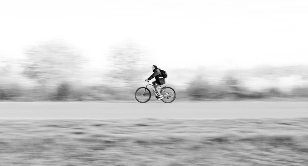 Zdjęcie ilustracyjne: fotografia w biało-czarnych odcieniach cyclisty. W czasie wyprzedzania potrącił rowerzystów i uciekł. Policja szuka kierowcy busa. Fot. Alex Dos Santos / Pexels