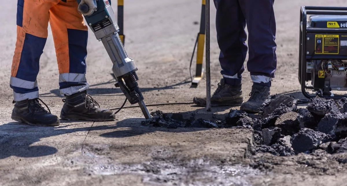 Zdjęcie ilustracyjne: robotnicy budowlani rozbijają asfalt młotem pneumatycznym podczas prac. Ulica Kamienna do remontu – nowa, wzmocniona nawierzchnia już za miesiąc. Fot. Sergei Starostin / Pexels